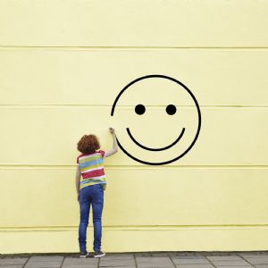 picture of girl drawing a face on the wall